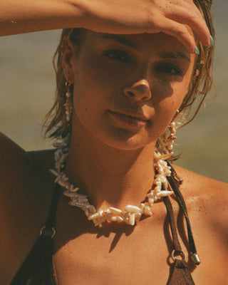 Model wearing a pearl necklace with a blurred background