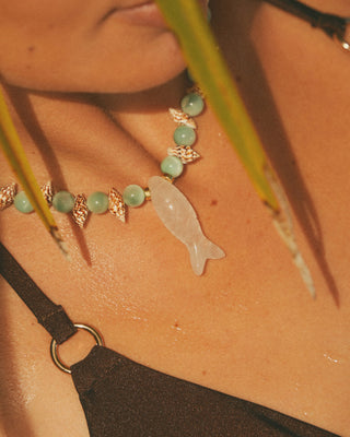 Necklace with moonstone beads and a fish pendant on a model's neck.