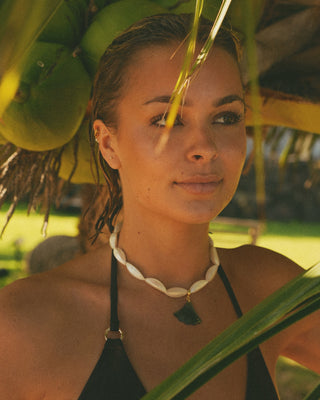 Model with a necklace standing under a palm tree