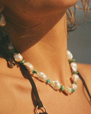 Necklace with pearls and green accents on a person's neck
