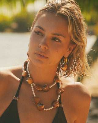 Model wearing a pearl and shell necklace with shell earrings