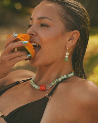 Model eating a piece of fruit outdoors with a moonstone necklace