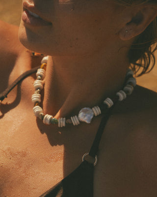 Close-up of a model wearing a beaded necklace with a blurred background