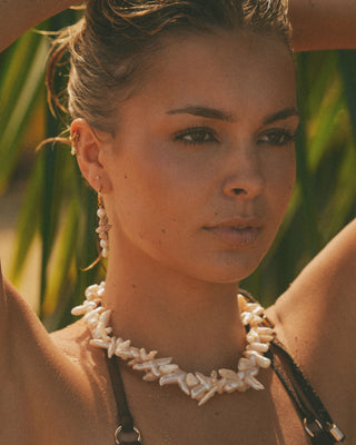 Woman wearing the blair necklace and the Sierra earrings with a blurred natural background
